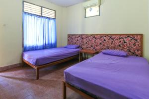 库塔梅尔纱雅缇酒店的配有紫色床单和窗户的客房内的两张床