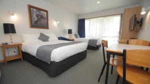 基督城ASURE Christchurch Classic Motel & Apartments的酒店客房设有两张床和一张桌子。