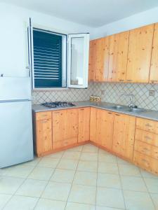 莱乌卡Casa vacanza Leuca的厨房配有木制橱柜和白色冰箱。