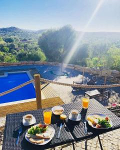 埃斯托伊Villa Monte da Alfarrobeira的一张带食物和饮料的桌子,享有游泳池的景色