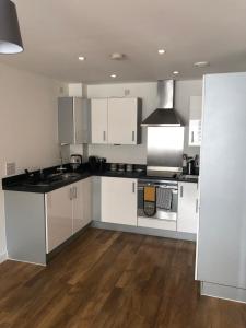 卡迪夫Quayside Apartment in Cardiff Bay的厨房配有白色橱柜和黑色台面