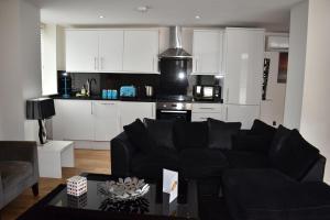 伦敦Luxlogic的一间带黑色沙发的客厅和一间厨房