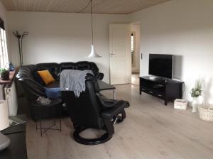 吉弗Ny istandsat træhus i Givskud的客厅配有真皮沙发和电视