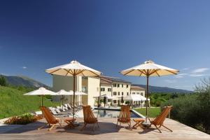 维托里奥·威尼托Colonìa Resort的一组椅子和遮阳伞,位于游泳池旁