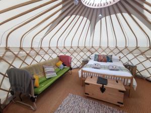 巴特米尔Syke Farm Campsite - Yurt's and Shepherds Hut的蒙古包内带一张床和一张沙发的房间