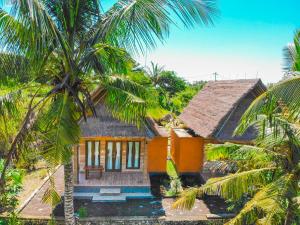珀尼达岛Batang Golden Hills的一座带茅草屋顶和棕榈树的小房子