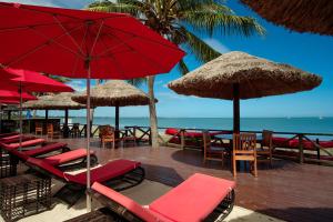 南迪斐济威洛艾洛海滩华美达酒店 的海滩上的一组椅子和遮阳伞