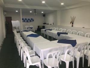 基布多Hotel el imperio的一间设有一排桌子和白色椅子的房间
