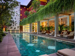 库塔库塔阿姆纳雅酒店的酒店游泳池设有椅子,酒店大楼