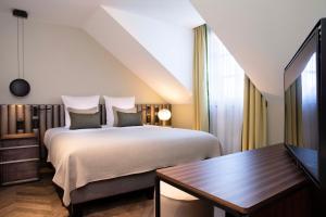 日内瓦Hotel D Geneva的一间卧室配有一张床、一张桌子和一台电视
