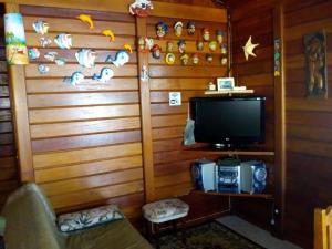 伊利亚孔普里达Ilha Comprida-Casa Madeira-Conforto Familiar的一间带电视和沙发的墙壁的房间