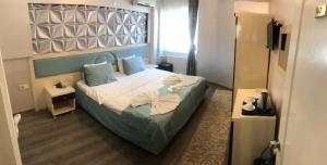 伯萨汉柯大酒店的一间卧室配有一张带蓝色枕头的床。