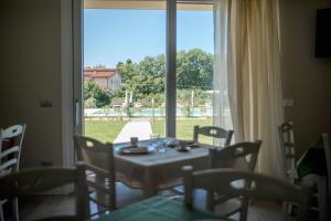 拉齐塞Menta e Rosmarino Rooms的一间带桌椅和大窗户的用餐室
