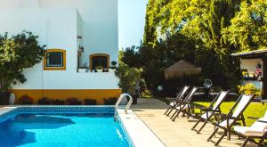 维拉诺瓦德卡塞拉卡萨代卡塞拉韦旅馆的房屋旁的游泳池配有椅子和桌子