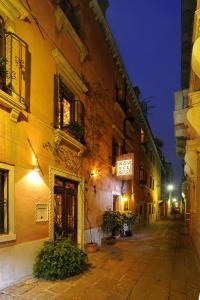 威尼斯Novecento Boutique Hotel的夜间一条空的街道,在建筑物上标有标志
