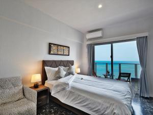 北谷町Beach Front Tower Mihama by DSH的卧室配有床、椅子和窗户。