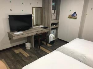新竹心園生活旅店 Xin Yuan Hotel的客房设有一张桌子、一台电视和一张床
