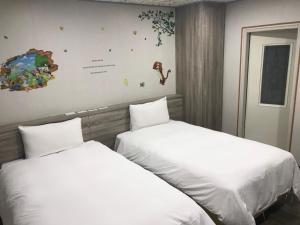 新竹心園生活旅店 Xin Yuan Hotel的两张睡床彼此相邻,位于一个房间里