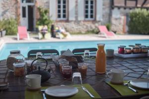 Lescure-dʼAlbigeois佩妮酒店的游泳池旁的餐桌上摆放着食物和饮料