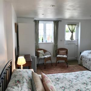 特鲁罗Jago Cottage的一间卧室配有两张床、一张桌子和两把椅子