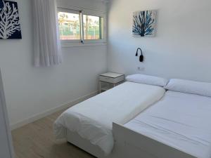 蒂亚斯Teiga Playa的一间白色卧室,配有两张床和窗户