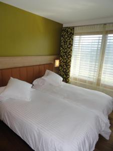 RevòViridis Hotel的卧室内的一张大白色床,带有窗户