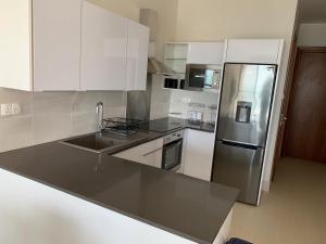 Sere Kunda NDingWATERFRONT FLAT的厨房配有白色橱柜和不锈钢冰箱