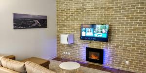 鲁昂Appart'HomeCity - Rouen Grand Voile的客厅设有壁炉和砖墙上的电视