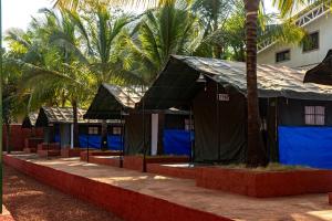 达博利Tent-O-Treat Premium Rooms near Dapoli的棕榈树前的一排帐篷