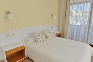 Naveces滨海公寓的白色的卧室设有白色的床和窗户。