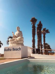 圣玛丽亚Hotel LIVVO Budha Beach的棕榈树泳池旁的雕像