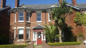 法恩伯勒Colebrook Guest House的一间砖房,有红门和棕榈树