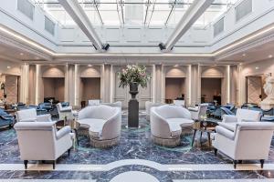 里昂Boscolo Lyon Hotel & Spa的大堂设有白色的椅子和桌子,并鲜花盛开