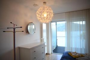 沃尔特湖畔佩莎赫希码头公寓的一间带吊灯和白色梳妆台的卧室以及一间客房。