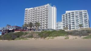 莫塞尔湾Beach Club Self Catering Apartments的海滩上一座白色的大建筑,种有棕榈树