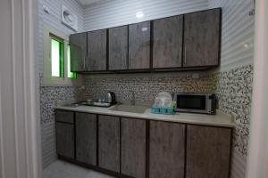 延布Jasmine Beach Hotel Suites的厨房配有木制橱柜、水槽和微波炉