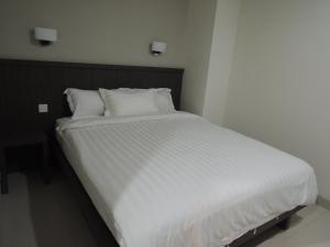 雅加达哈利斯公寓的一张带白色床单和枕头的床