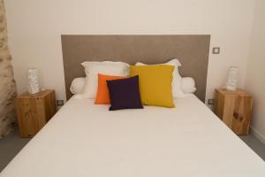 索泰尔纳Hôtel Le 23的卧室配有白色的床和色彩缤纷的枕头