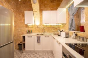 比尔古16 lettings - charming character house的厨房配有白色橱柜和石墙
