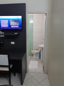 大瓦尔泽亚Hotel Express - Leva e busca no aeroporto grátis 24 horas的一间带壁挂式电视和卫生间的浴室