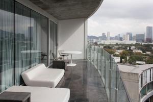 蒙特雷Habita Monterrey, a Member of Design Hotels的阳台配有白色家具,享有城市美景。