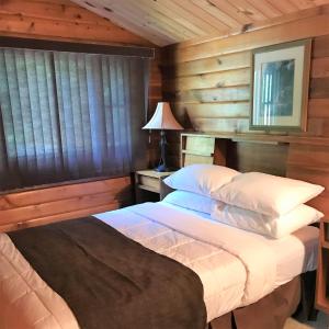 Oxtongue Lake三叶草别墅酒店的卧室配有一张床铺,位于带木墙的房间内