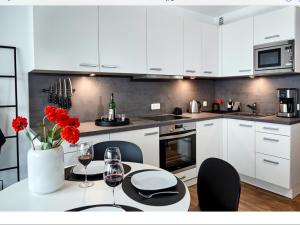 特拉弗明德Grünstrand的厨房配有白色橱柜和红色鲜花桌