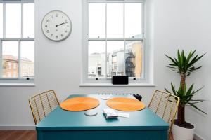 伦敦Crashpads Shoreditch the Club Row Collection的一张蓝色的桌子和椅子,位于一个钟表的房间