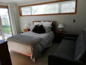 基督城Whaka Heights的一间卧室配有一张床、一张沙发和一个窗口