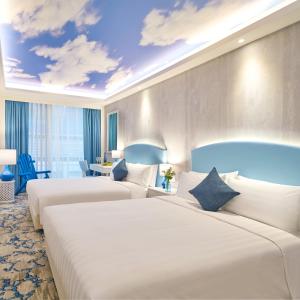 香港悦品度假酒店(屯门)的蓝色天空和云彩壁画的酒店客房内的两张床