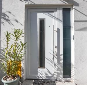 萨格勒布Apartman Zagreb Maksimir的白色房子上一扇白色门,两棵植物