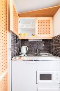 萨翁林纳罗西兰塔旅舍的小厨房配有白色橱柜和水槽