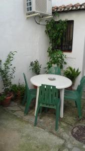 JubriqueJúbrique的大楼旁的一张白色桌子和两张绿色椅子