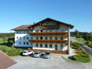 海德米赫莱Hotel Märchenwald的一座白色的大建筑,汽车停在停车场